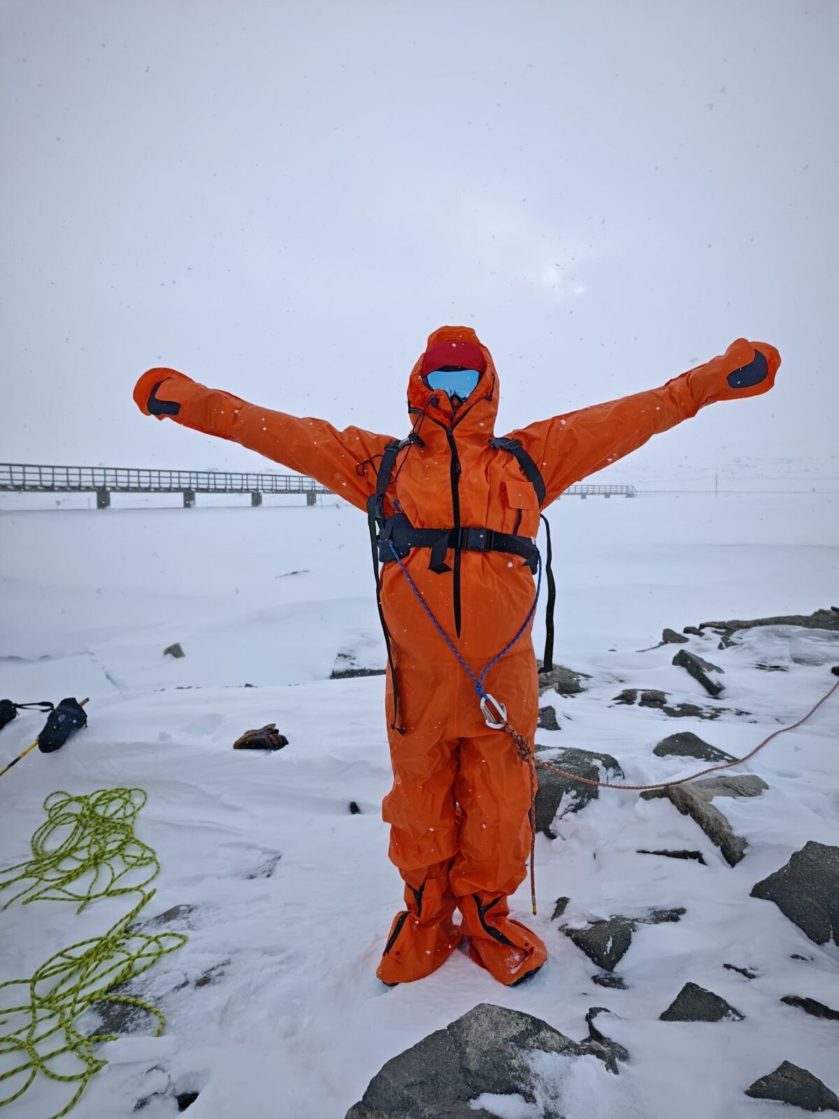 Sealed into an immersion dry suit, arms out, ready for the icy-water crossing drill on polar survival training